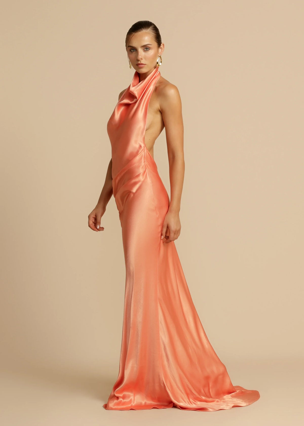 Arcina Ori Gaia Dress Hire in papaya – bias-cut gown with cowl neckline and low open back.