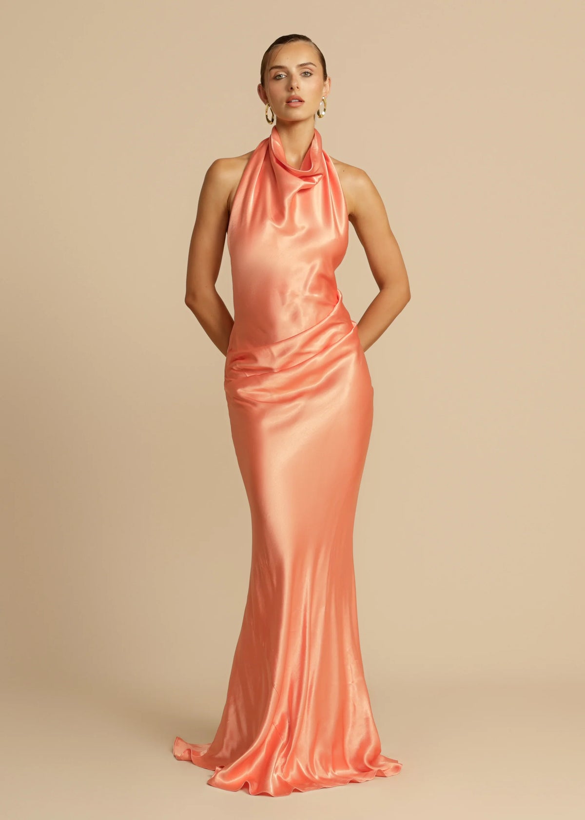 Arcina Ori Gaia Dress Hire in papaya – bias-cut gown with cowl neckline and low open back.