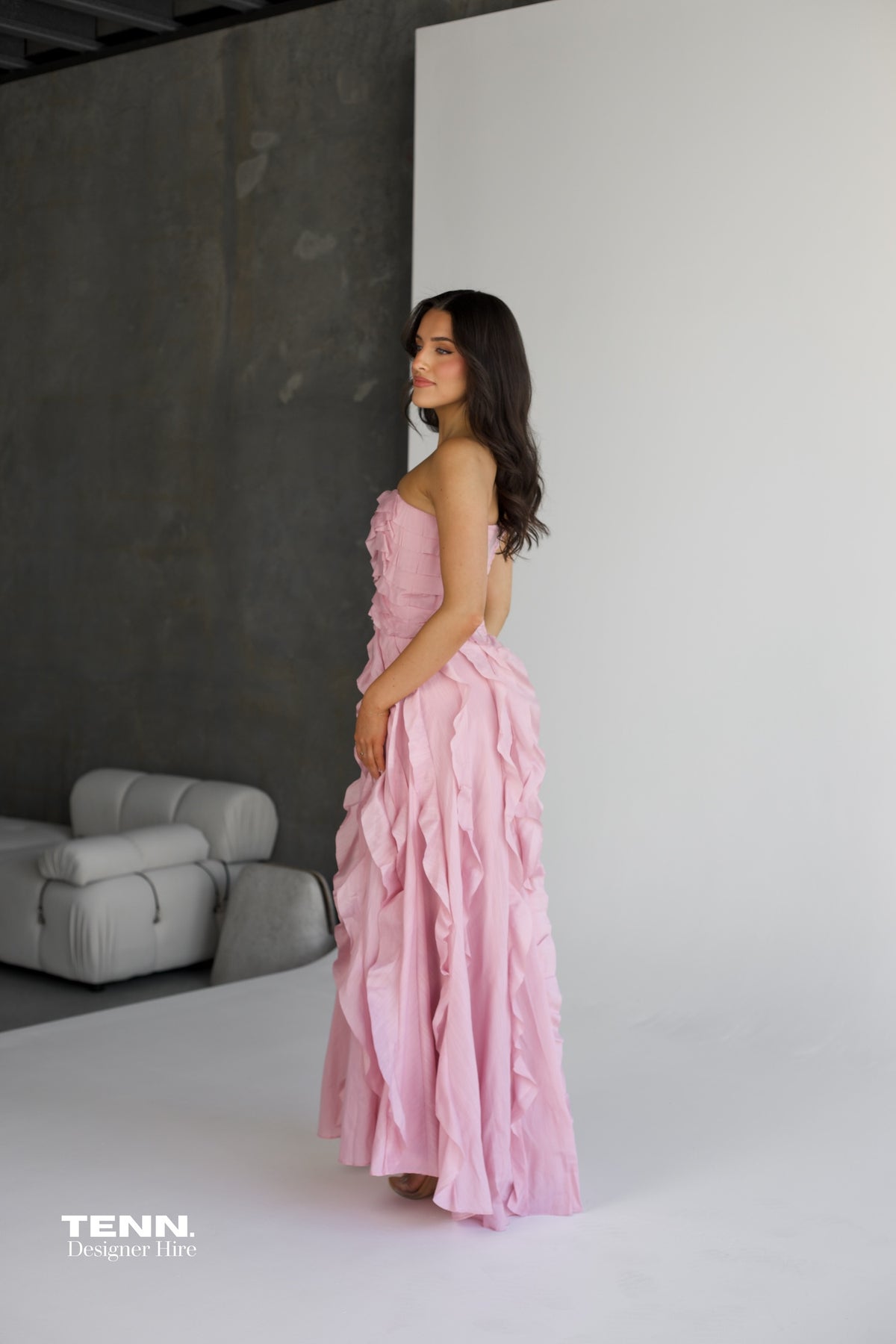 Aje Allairie Gown in pink available for hire at TENN Designer Hire — elegant strapless formal gown with asymmetric cascading ruffles and flowing voluminous skirt, perfect for garden weddings and summer events.