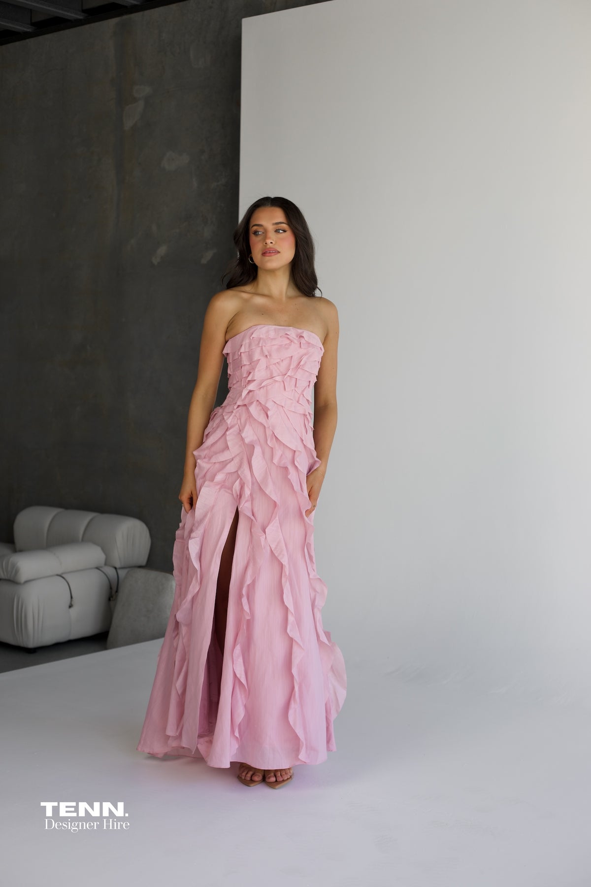 Aje Allairie Gown in pink available for hire at TENN Designer Hire — elegant strapless formal gown with asymmetric cascading ruffles and flowing voluminous skirt, perfect for garden weddings and summer events.